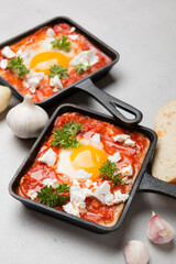 Fried eggs with tomatoes and cheese in a frying pan. Shakshuka, a Jewish dish.
