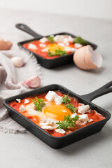 Fried eggs with tomatoes and cheese in a frying pan. Shakshuka, a Jewish dish.
