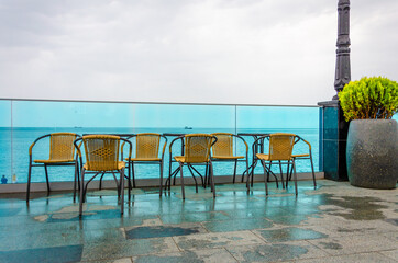 Tables and chairs after the rain near the sea.