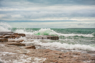 Dramatic scene with Sea waves, rocky seashore and clouds