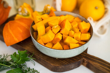 Close up of a plate with raw pumpkin pieces on kitchen table. Positive yellow backgorund. Autumn concept. Thanksgiving day