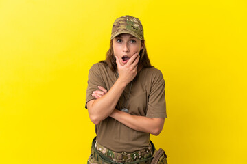 Military caucasian woman with dog tag isolated on yellow background surprised and shocked while looking right