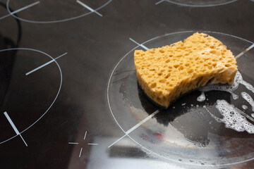 Sponge in foam on the stove. Cleaning the kitchen. Place for your text. Copy space.