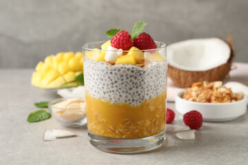 Delicious chia pudding with mango, raspberries and granola on light grey table