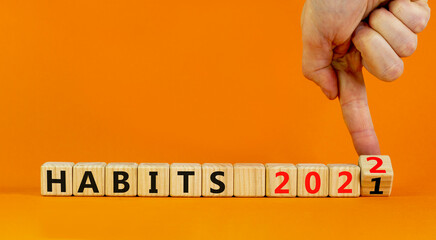 2022 habits and new year symbol. Businessman turns wooden cubes and changes words 'habits 2021' to 'habits 2022'. Beautiful orange background, copy space. Business, 2022 habits and new year concept.