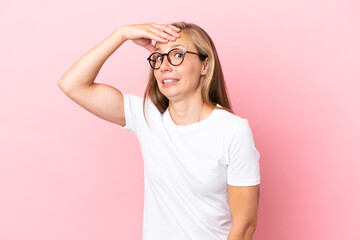 Young English woman isolated on pink background doing surprise gesture while looking to the side