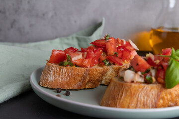 Two slices of tomato bruschetta made from ciabatta bread with diced tomatoes, spices, basil and chopped garlic on a plate, Italian cuisine, selektive focus