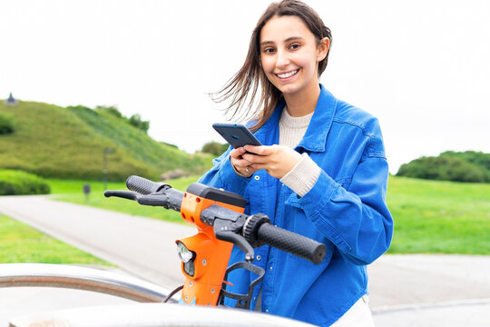 Happy woman using using kick sharing app to rent scooter