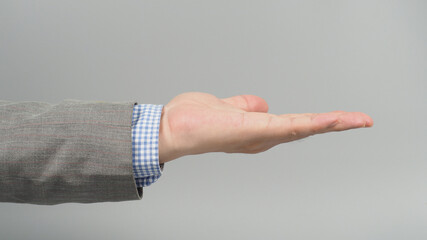 Empty Hand gesture in grey suit on grey background. Businessman topic