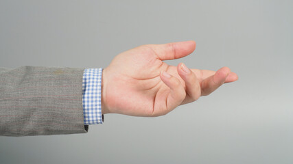 Obraz premium Empty Hand gesture in grey suit on grey background.