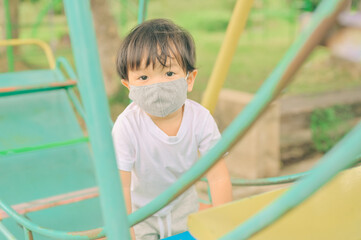 Little boy playing in the playground, the child is wearing a protective mask on the face during the quarantine of coronavirus, covid-19, virus protection.