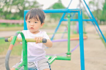 Little boy, kid having fun on swings at playground