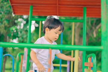 Fototapeta premium Little boy, kid having fun on swings at playground