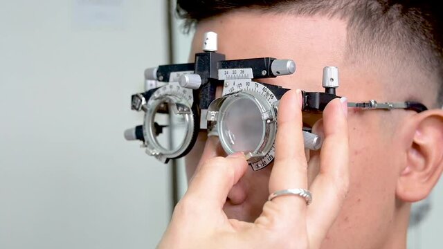 hombre joven con lentes de prueba en examen de la vista 