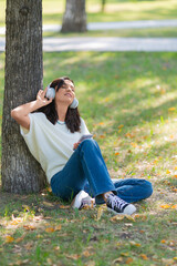 40-year-old woman wearing headphones with a smartphone. She listens to her favorite music while...