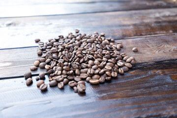 Roasted coffee grains on a wooden table close-up.