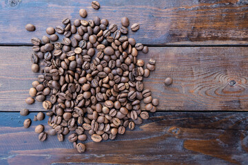 Roasted coffee grains on a wooden table close-up.