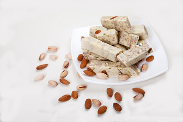 Halva made from sunflower seeds, almonds and pistachios lies on a plate on a white background. Copy spaes.
