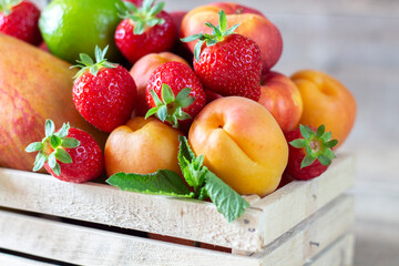 Fresh juicy fruits in basket on wooden background