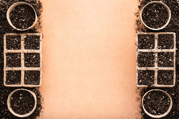 Biodegradable peat pots and peat trays filled with potting soil made of peat, worm humus and perlite, on a raw surface with copy space in the middle, seed starting concept.