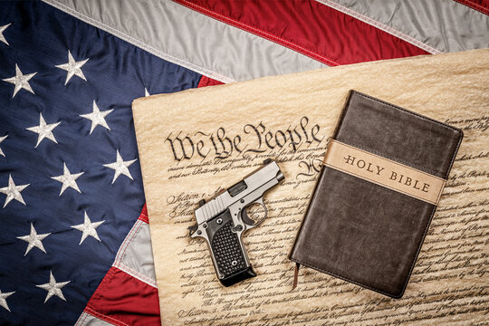 Holy Bible And Gun On Constitution And American Flag