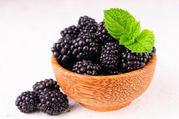 Blackberries in a wooden bowl on a white background.
Close-up.