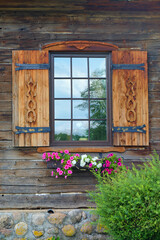 window with wooden shutters in a rustic house decorated with flowers