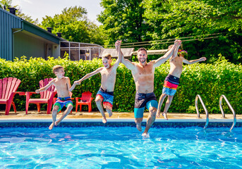 Father and sons having fun jumping on swimming pool