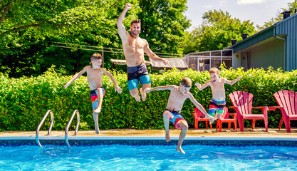 Father and sons having fun jumping on swimming pool