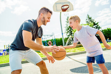 Happy basketball family portrait play this sport on summer season. The father play with boy