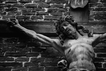 The crucifixion of Jesus Christ as a symbol of God's love. Antique statue. Black and white horizontal image.