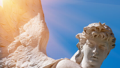 Angel with wings against blue sky. Ancient statue. Horizontal image.
