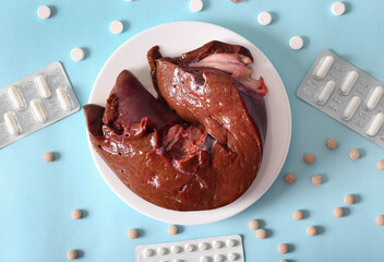 Beef liver and medicines on a blue background. Iron level. Raising hemoglobin. Damage to the liver. Healthy foods. Proper nutrition.