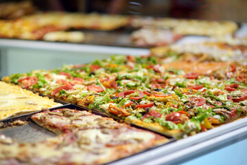 Square pieces of pizza displayed on the counter of small italian pizzeria in Bergamo city