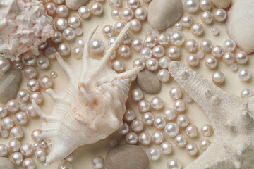 Beautiful sea shells, starfish, pebbles and pearls on beige background, flat lay