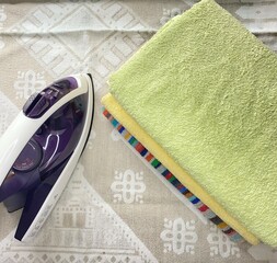 Housework, ironing iron colorful towels on the ironing board.