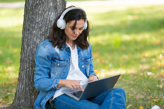 Cropped photo of a 40-years-old woman with laptop in city park during online vido call. Online working concept.