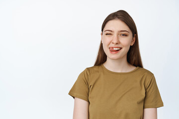 Dental clinic and stomatology concept. Happy young woman showing her white teeth and tongue, smiling at camera, white background