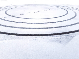 Fototapeta na wymiar First snow. An imprint of the wheels of a car in a circle and a man steps diagonally.