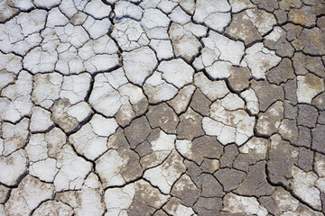 A dry, lifeless, barren clay land cracked in the African desert during global warming and climate change. A hot surface during drought is destroyed, eroded and textured. Copy space, background.