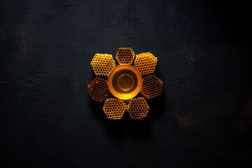 Honey and honeycomb in the form of a flower on black table, top view. space for text