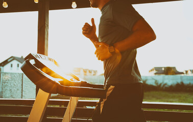 The guy jogging on treadmill on terrace of his home. Social isolation or quarantine concept