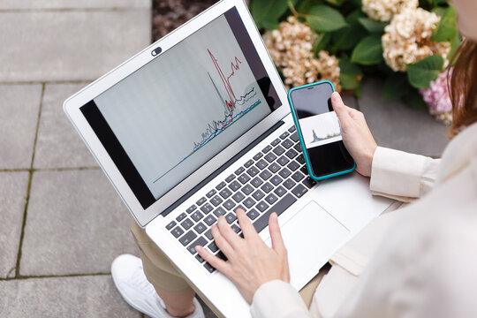 woman holding laptop and smartphone watching bitcoin growth chart