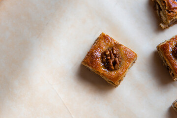 a piece of baklava cake with walnuts on baking paper. Horizontal photo