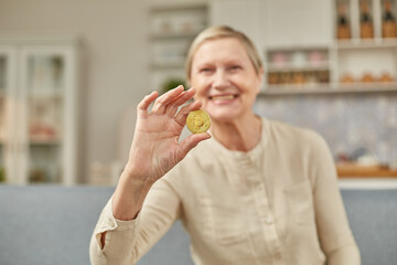 An elderly woman holds a bitcoin coin in her hand. Happy retirement life concept