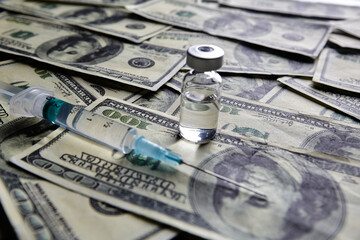 Vaccine vial and syringe on the background of one hundred dollar bills