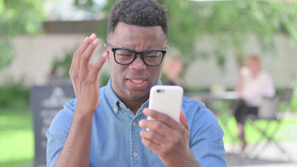 Outdoor African Man Reacting to Loss on Smartphone
