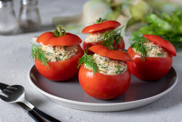 Stuffed tomatoes with cheese, dill and garlic on a gray plate on a light background