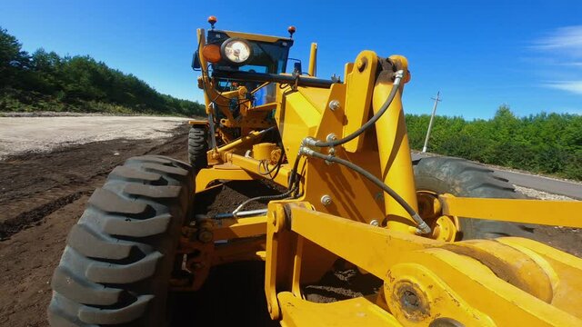 Grader is leveling ground, working at construction of new road, onboard camera