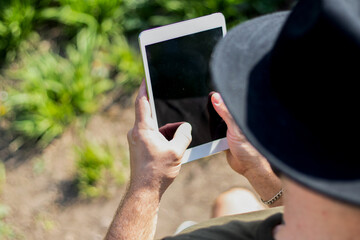 Close up of a tablet held by a man with hat.